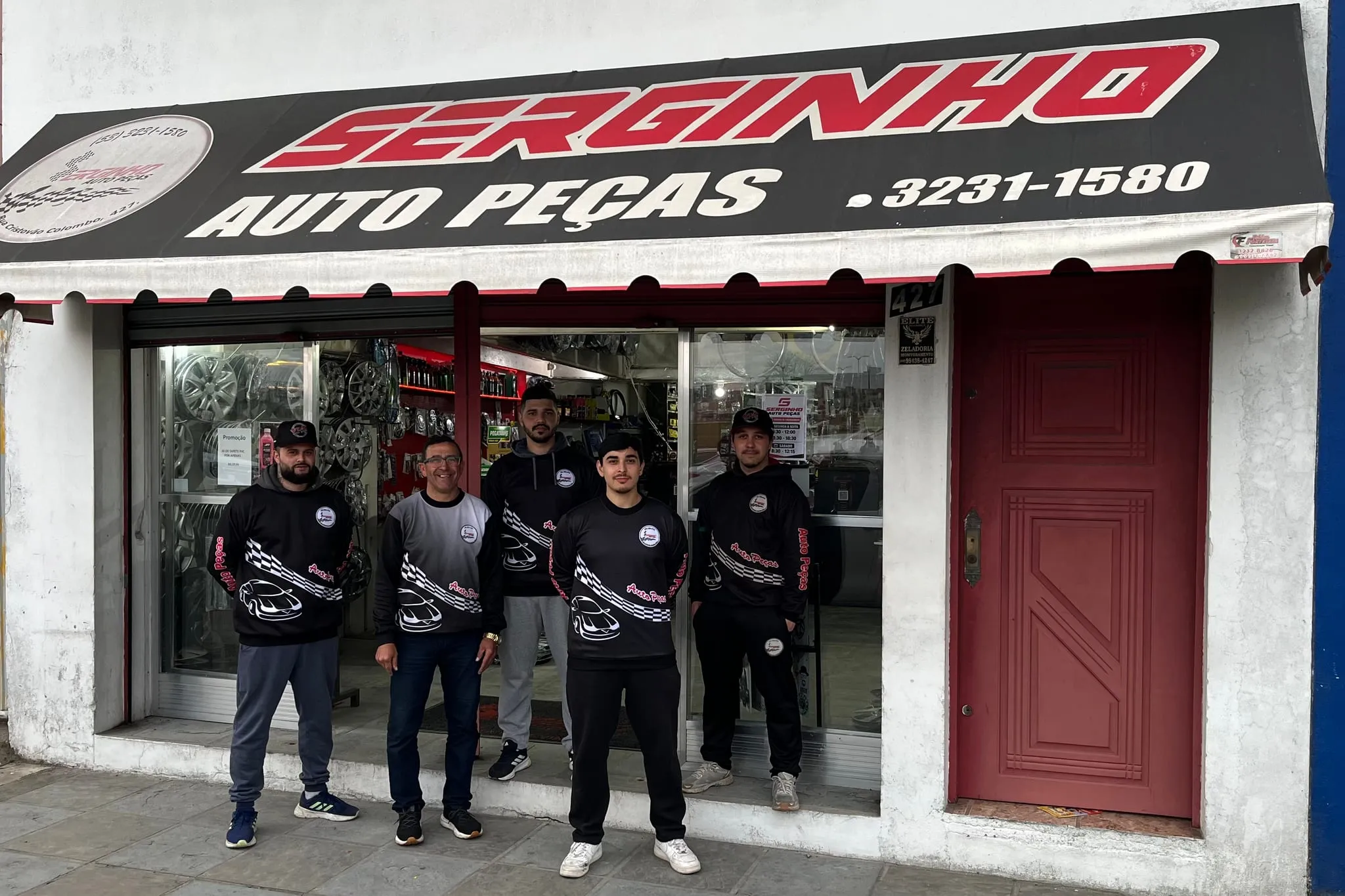 Equipe da Serginho Autopeças, cinco pessoas de uniforme, na porta da loja na Rua Cristóvão Colombo, 427